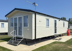 A mobile home with a front door, windows, and a small porch area.