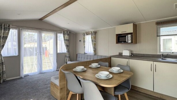 Una cocina compacta con una mesa de comedor lista para cuatro personas, un microondas y un tostador.