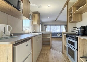 Cocina compacta con horno integrado, cafetera y ventana que proporciona luz natural.