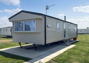 A mobile home with a covered porch, a satellite dish, and a small step leading to the entrance.