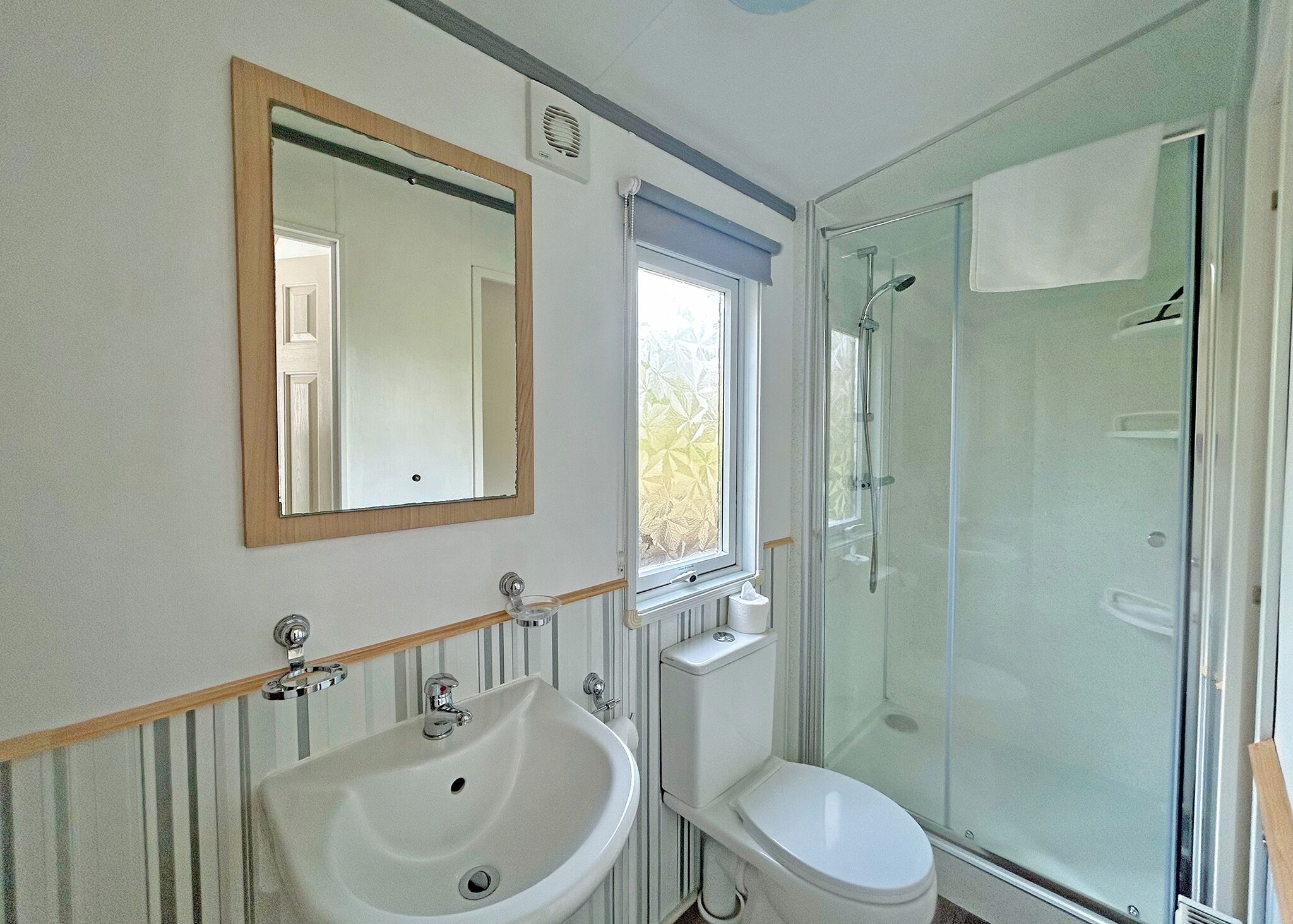 Et badeværelse med vask, toilet og bruser.