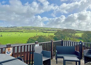 A deck with wicker furniture overlooking a green field with cows. - 2 bedroom accommodation in Tintagel (Tintagel)