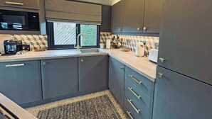 Een moderne keuken met grijze kastjes, een ingebouwde magnetron en een raam met uitzicht op groen.