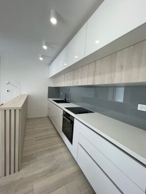 Eine moderne Küche mit weißen Schränken, einer Holz Arbeitsplatte und einem eingebauten Backofen.