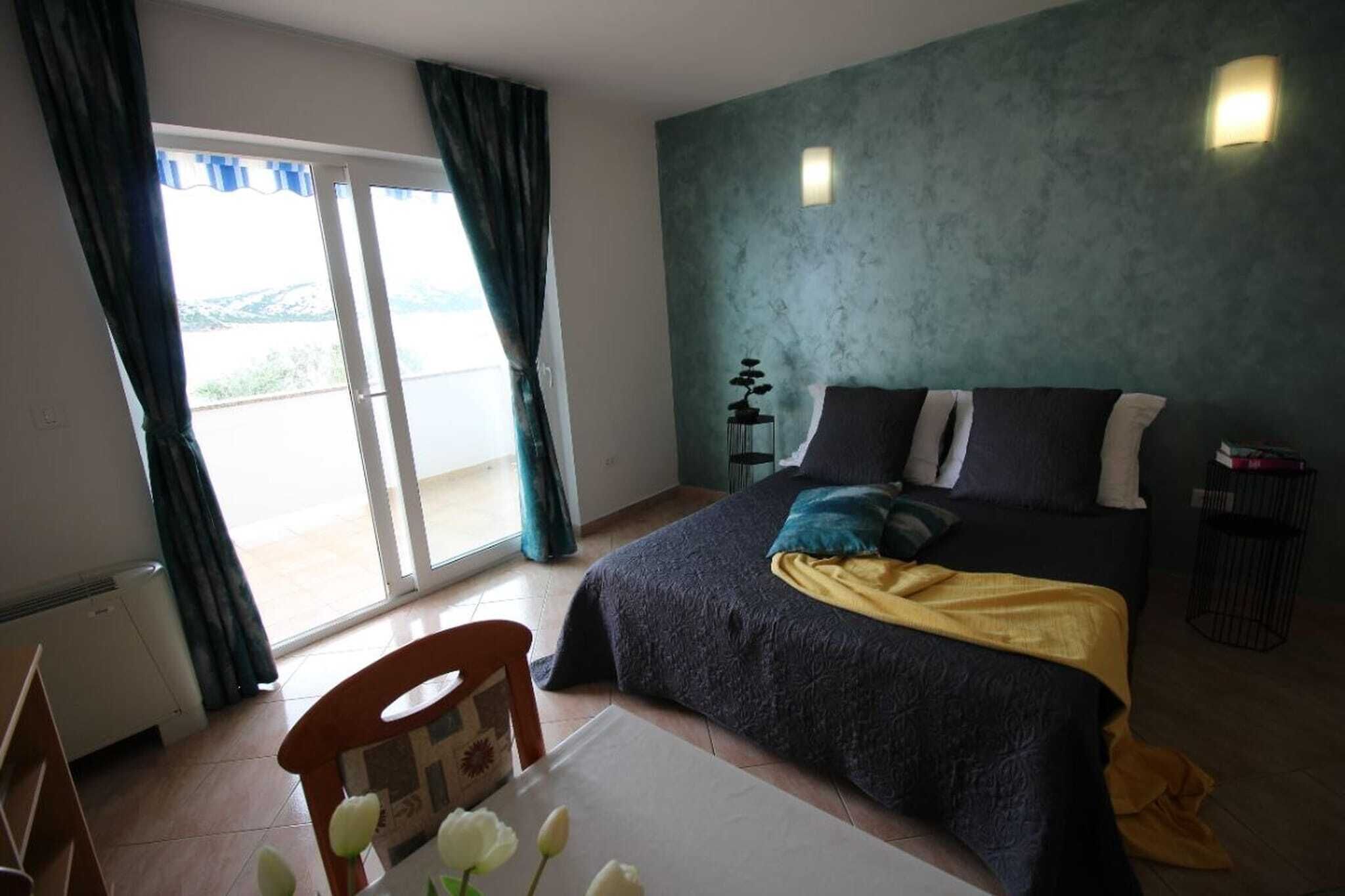 Une chambre à coucher avec un lit, une table ornée de fleurs, une chaise, une table de chevet, une lampe et une vue sur l’extérieur grâce à une porte coulissante.