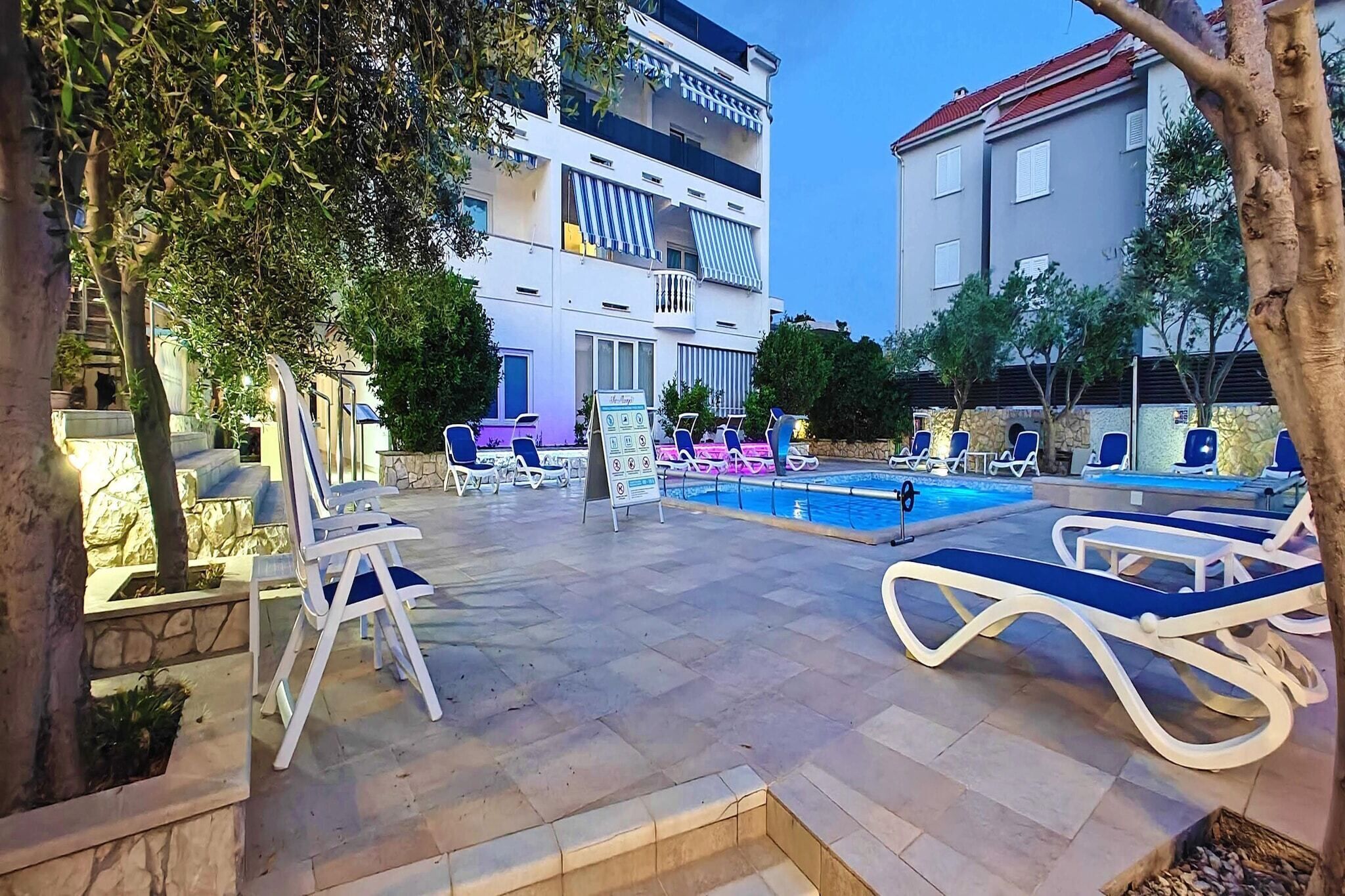 A poolside area with lounge chairs, a swimming pool, and a building with balconies.
