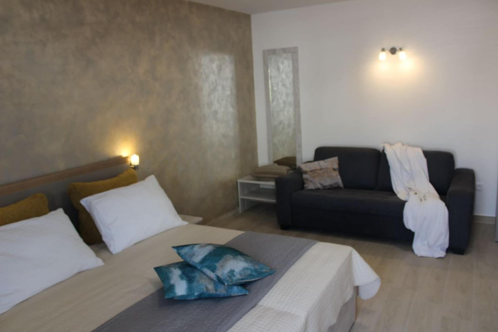 Quarto de hotel com cama, sofá e mesa de cabeceira.