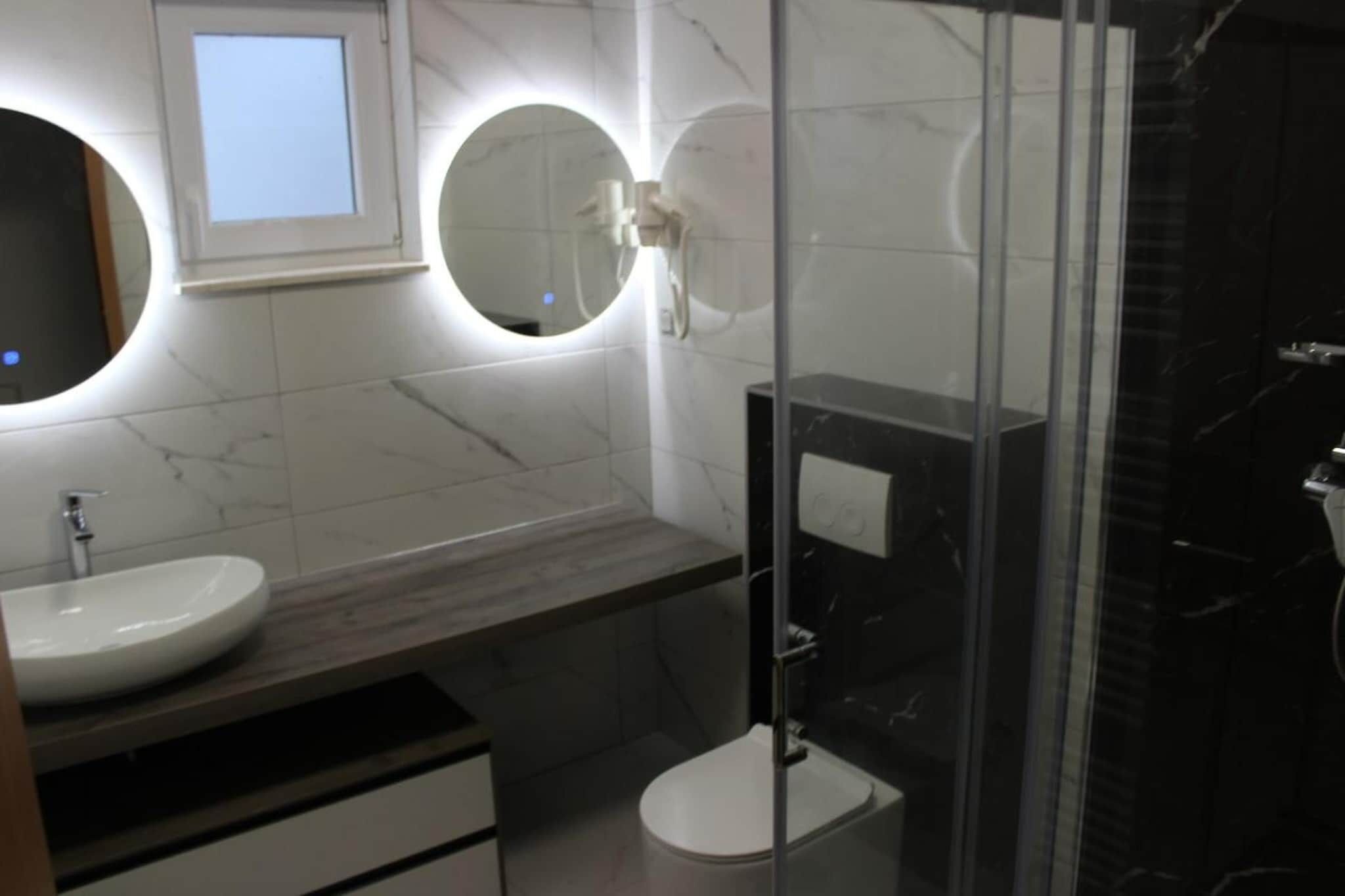 Une salle de bain moderne avec un miroir rond, un lavabo et des toilettes.