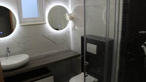 Een moderne badkamer met een ronde spiegel, een wastafel en een toilet.