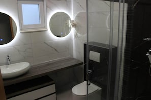 A modern bathroom with a round mirror, a sink, and a toilet. - Comfortable Croatian Couple Retreat (Stara Novalja)