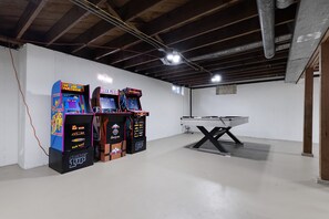 Une salle avec des bornes d’arcade et une table de ping-pong.