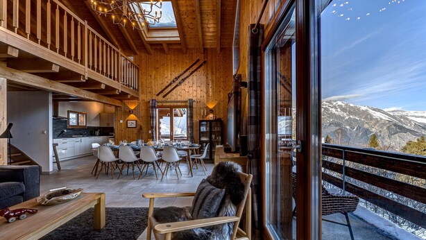 A spacious living area with a high ceiling, wooden beams, and a large window overlooking a snowy mountain. - Chalet Renard Roux - La Tzoumaz, 4 Vallees (La Tzoumaz)