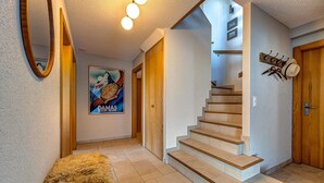 A staircase leading to a second floor, a wooden bench, a mirror, and a poster on the wall. - Chalet Renard Roux - La Tzoumaz, 4 Vallees (La Tzoumaz)