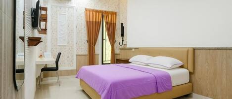 A bedroom with a bed, a desk, a chair, a TV, and a window with curtains.
