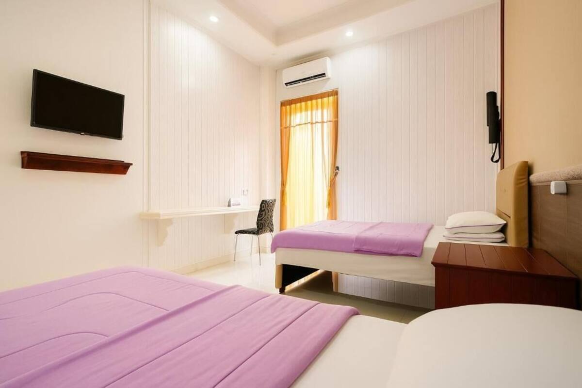 Habitación de hotel con dos camas, televisión, aire acondicionado, escritorio y una silla.