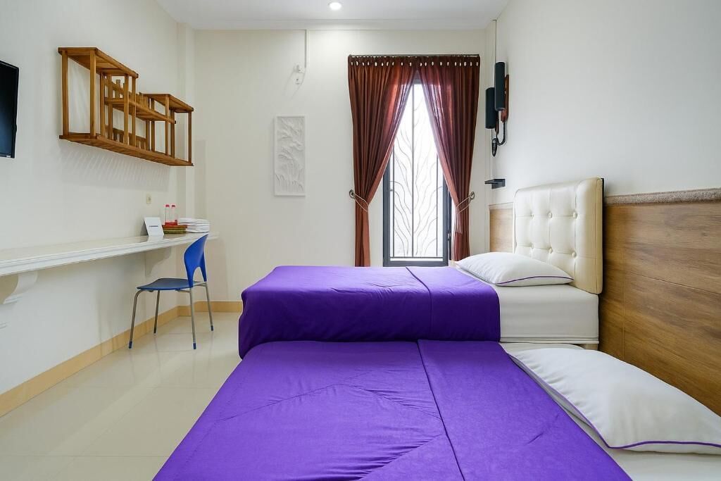 A room with a bed, a desk, a chair, and a window with curtains.
