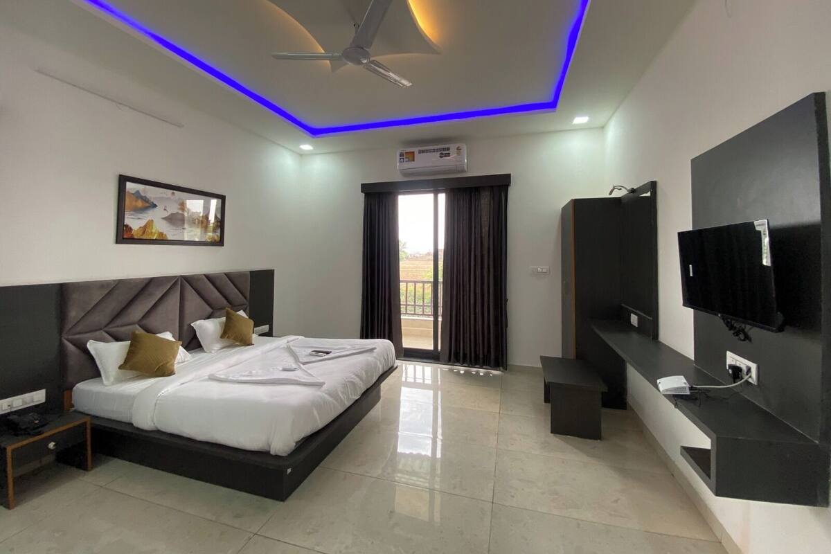 Una habitación de hotel moderna con una cama, un ventilador de techo, un televisor y un equipo de aire acondicionado.