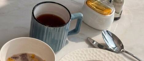 Un desayuno con un plato de cruasanes y tostadas, una taza de café y un bol de cereal.