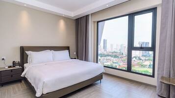 Una habitación de hotel moderna con una cama grande, una mesita de noche, un ventanal con vistas a la ciudad y una lámpara en el techo.
