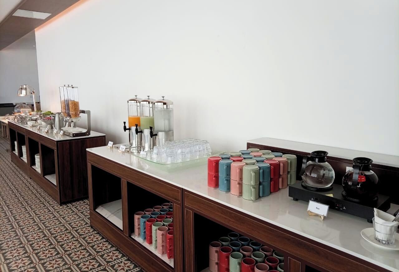 Un buffet avec différents récipients contenant de la nourriture, un coin café et un distributeur de boissons.