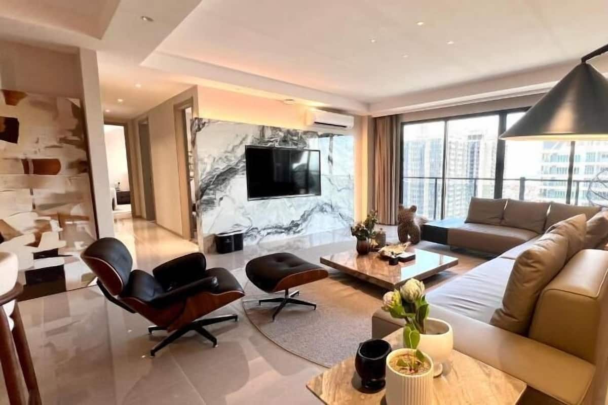 A modern living room with a sofa, chairs, a coffee table, and a TV.
