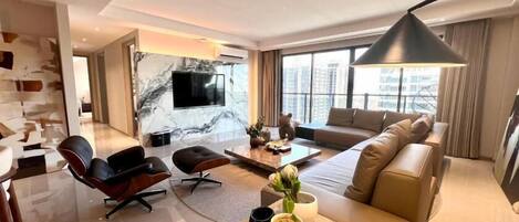 Ein modernes Wohnzimmer mit einer Couch, Sesseln, einem Couchtisch und einem Fernseher.