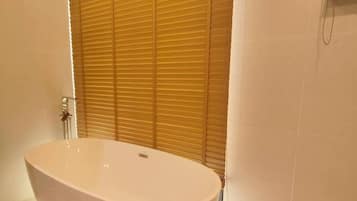 Une salle de bain moderne avec une baignoire sur pieds, des portes coulissantes en bois et des murs carrelés.