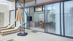 A modern outdoor area with a pool, sun loungers, a table, and a chair. - Samui Luxury villas-BySamui Rental  (Bueang Sam Phan)