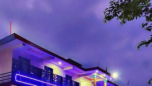 A two-story house with a balcony, illuminated by blue lights. - Yamunotri Darshan Resort By Preet rS (Rajgarhi)