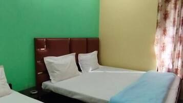 A hotel room with two beds, green and yellow walls, and a floral curtain.
