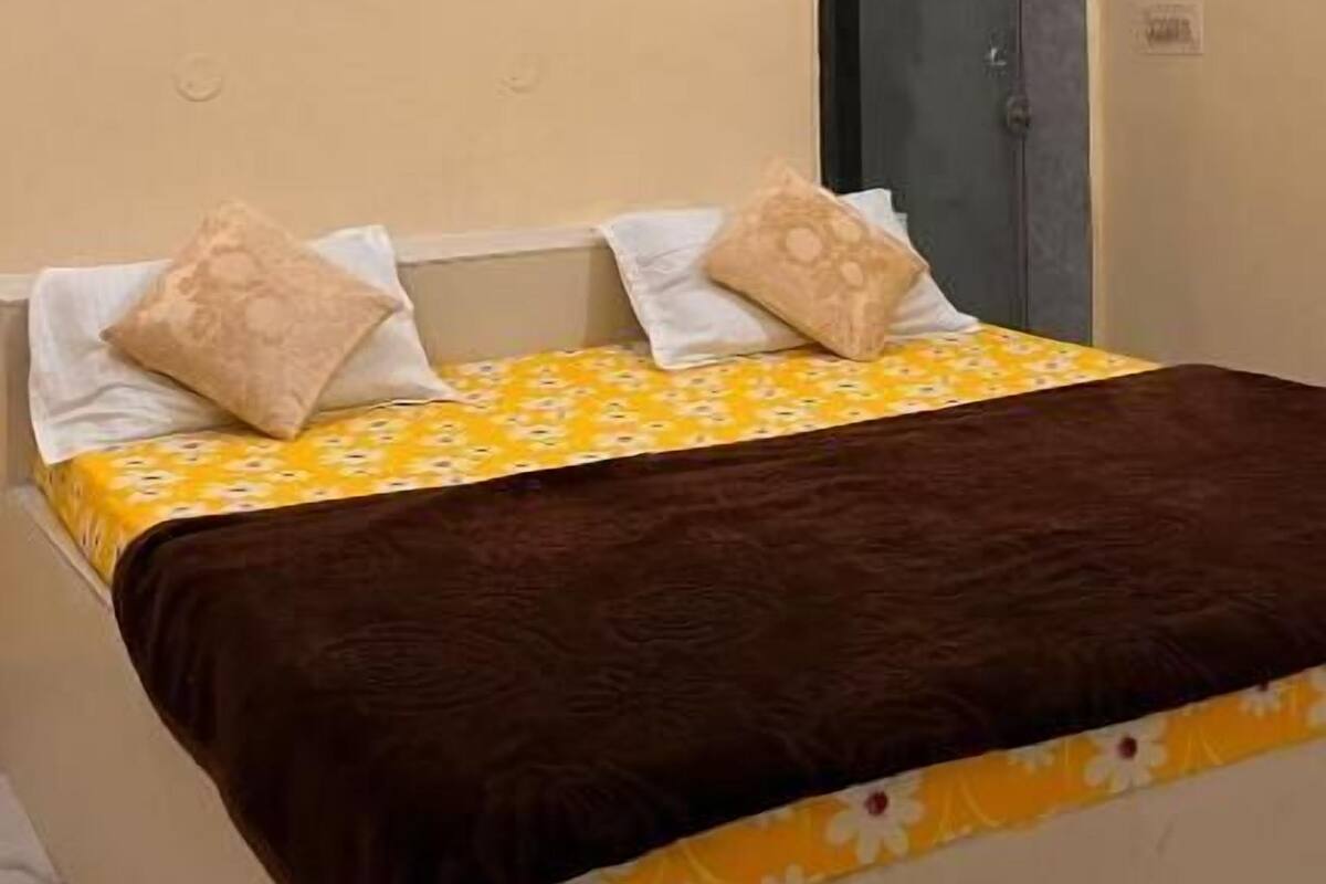 Ein Schlafzimmer mit einem Bett, zwei Kissen, einer braunen Decke, einer Wand-Klimaanlage und einer Tür.