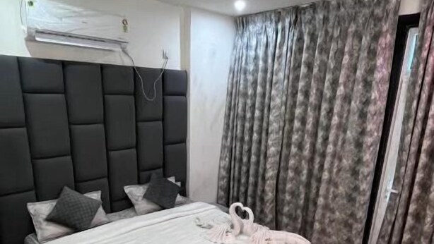Quarto com cama, cabeceira, janela com cortinas e aparelho de ar condicionado.