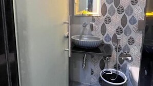 Um banheiro pequeno com pia, espelho e um balde.