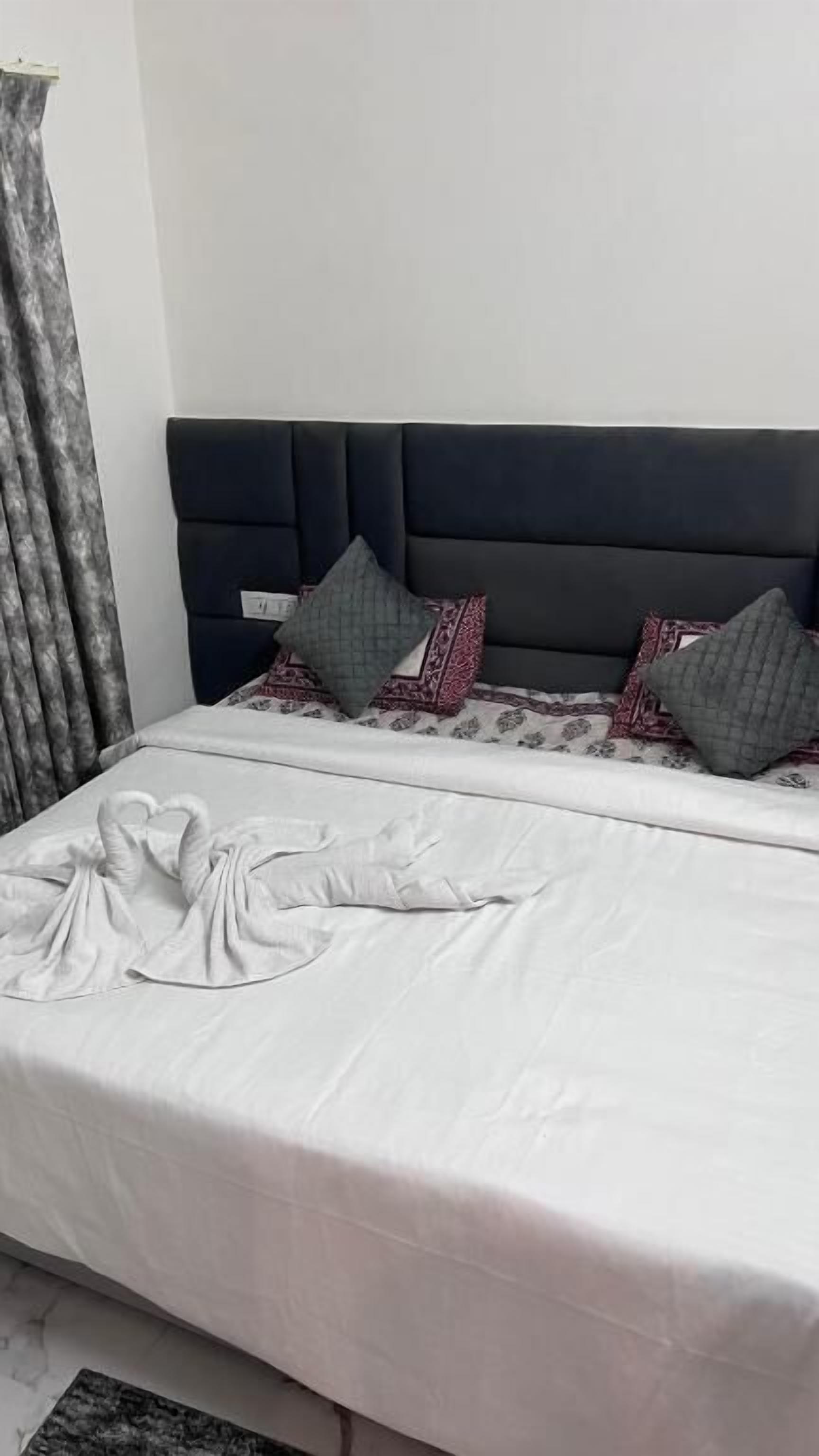 A neatly made bed with a white sheet and a heart-shaped pillow arrangement.