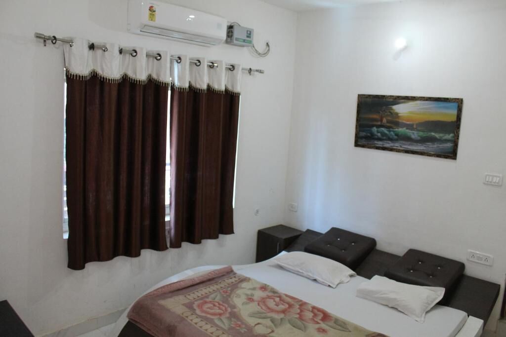 A bedroom with a bed, two nightstands, a painting on the wall, and a window with curtains.