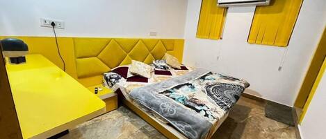 Una habitación con una cama, un escritorio amarillo y un equipo de aire acondicionado.