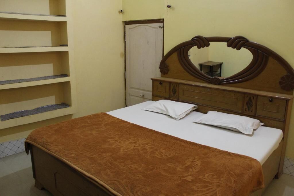A bedroom with a bed, a wooden dresser, a mirror, and a wardrobe.