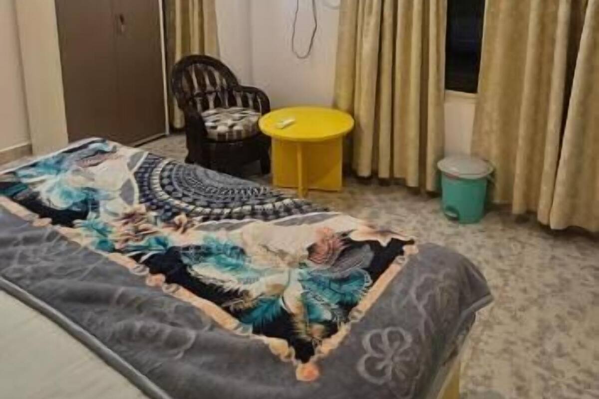 Ein Hotelzimmer mit einem Bett, einem Sessel, einem kleinen Tisch, einer Klimaanlage und Vorhängen.