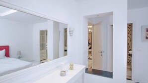 A modern bathroom with a large mirror, a white vanity, and a walk-in closet. - L'onde du Lac - Chic Apartment With Private Suite Prés Aéroprt et Cliniques (Tunis)