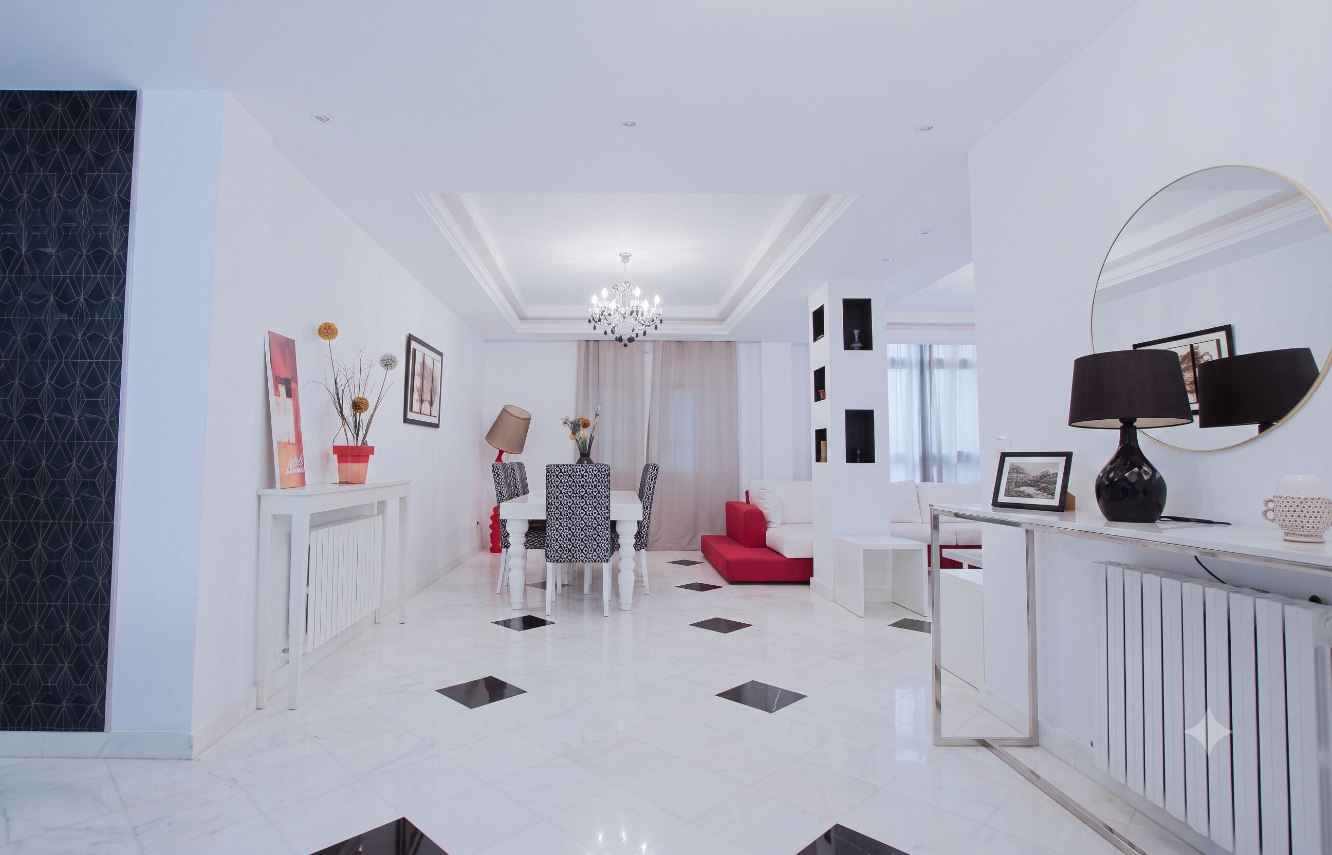 A modern interior with a dining area, a red sofa, a white console table, and a large mirror.