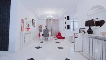 A modern interior with a dining area, a red sofa, a white console table, and a large mirror.