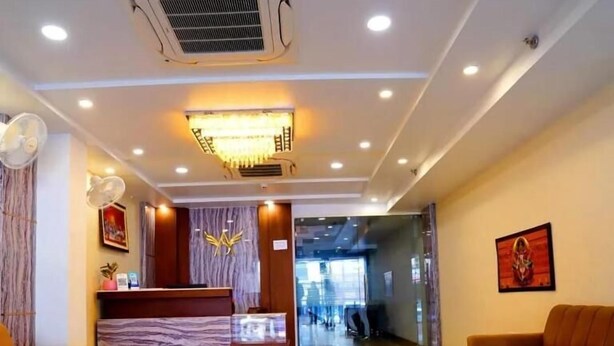 Eine Hotelhalle mit einer Rezeption, zwei Sofas, einem Marmorboden und einem Deckenventilator.