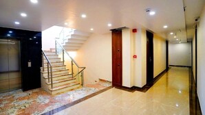 Eine Hotelhalle mit Marmorboden, einer Treppe, einer Holztür und einem Rauchmelder.
