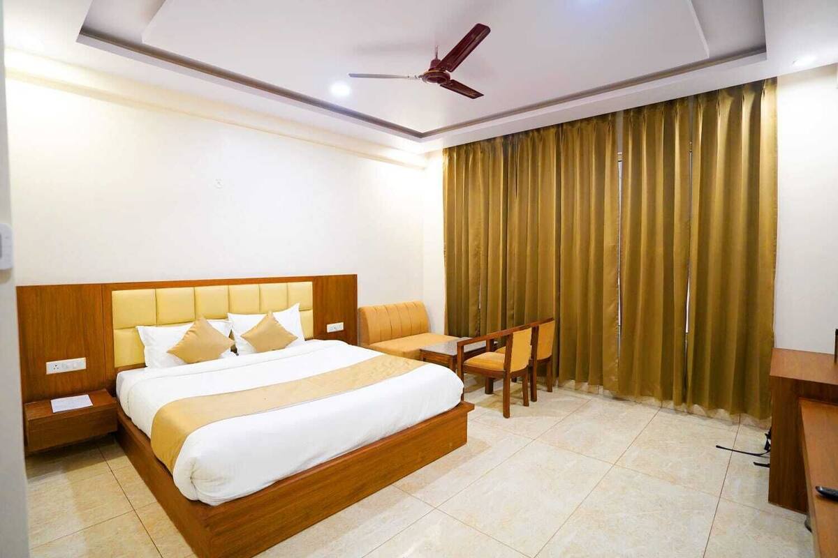 A hotel room with a large bed, a desk, and a chair.