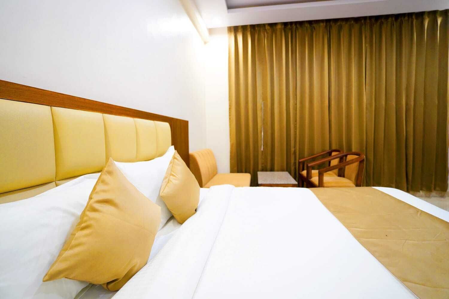 A hotel room with a large bed, a wooden headboard, a small table, and a chair.