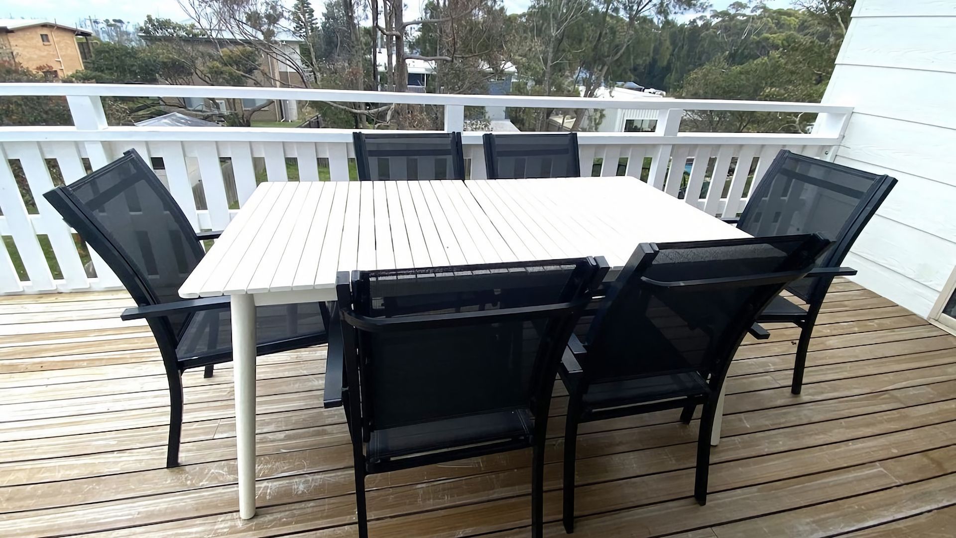 Une terrasse avec une table blanche et des chaises noires.