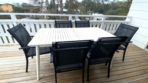 A deck with a white table and black chairs. - Coastal Holiday House (Manyana)