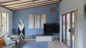 A living room with a sofa, a coffee table, a TV, and a sliding glass door leading to an outdoor area.
