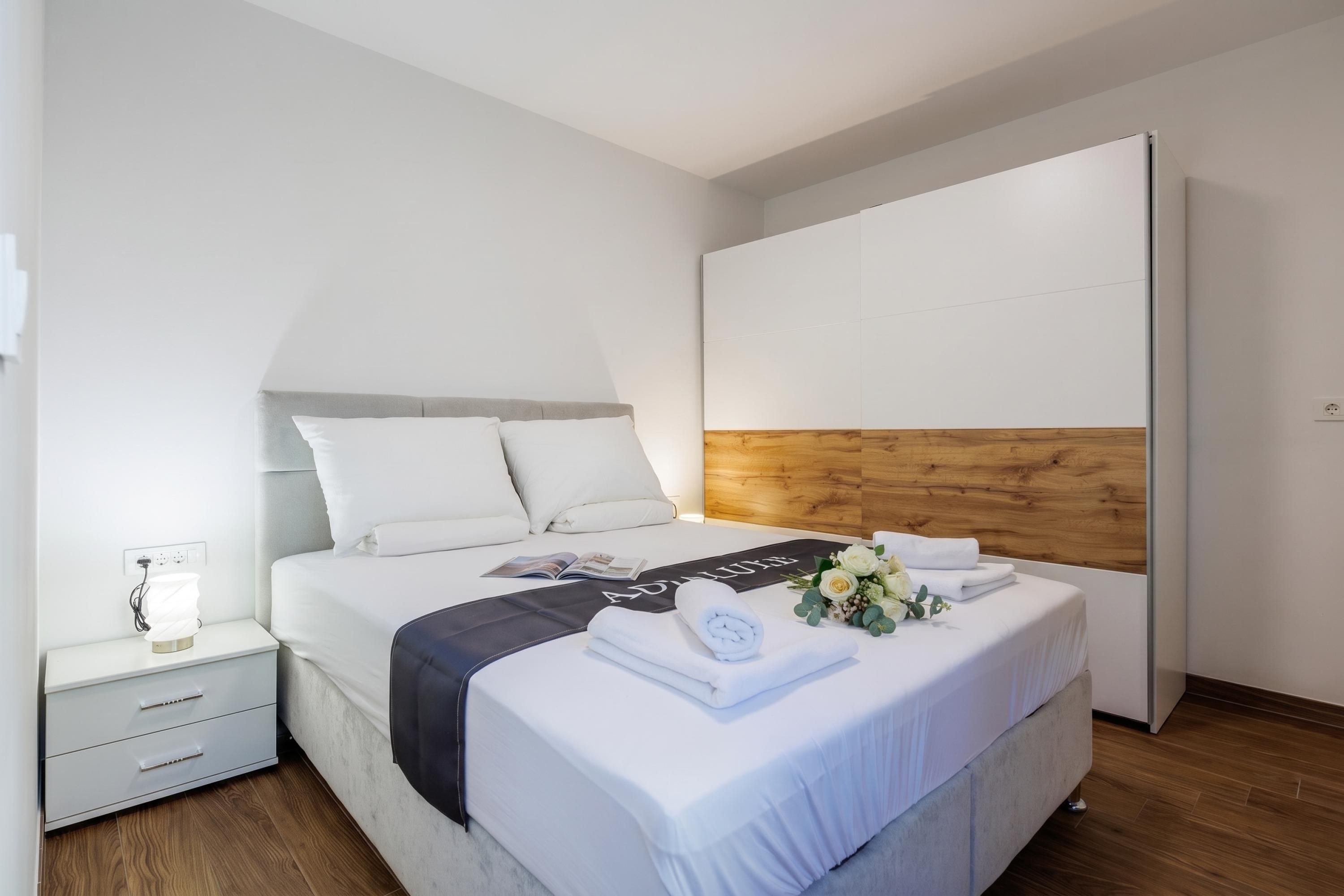Una habitación de hotel moderna con una cama, mesita de noche y cabecera de madera.