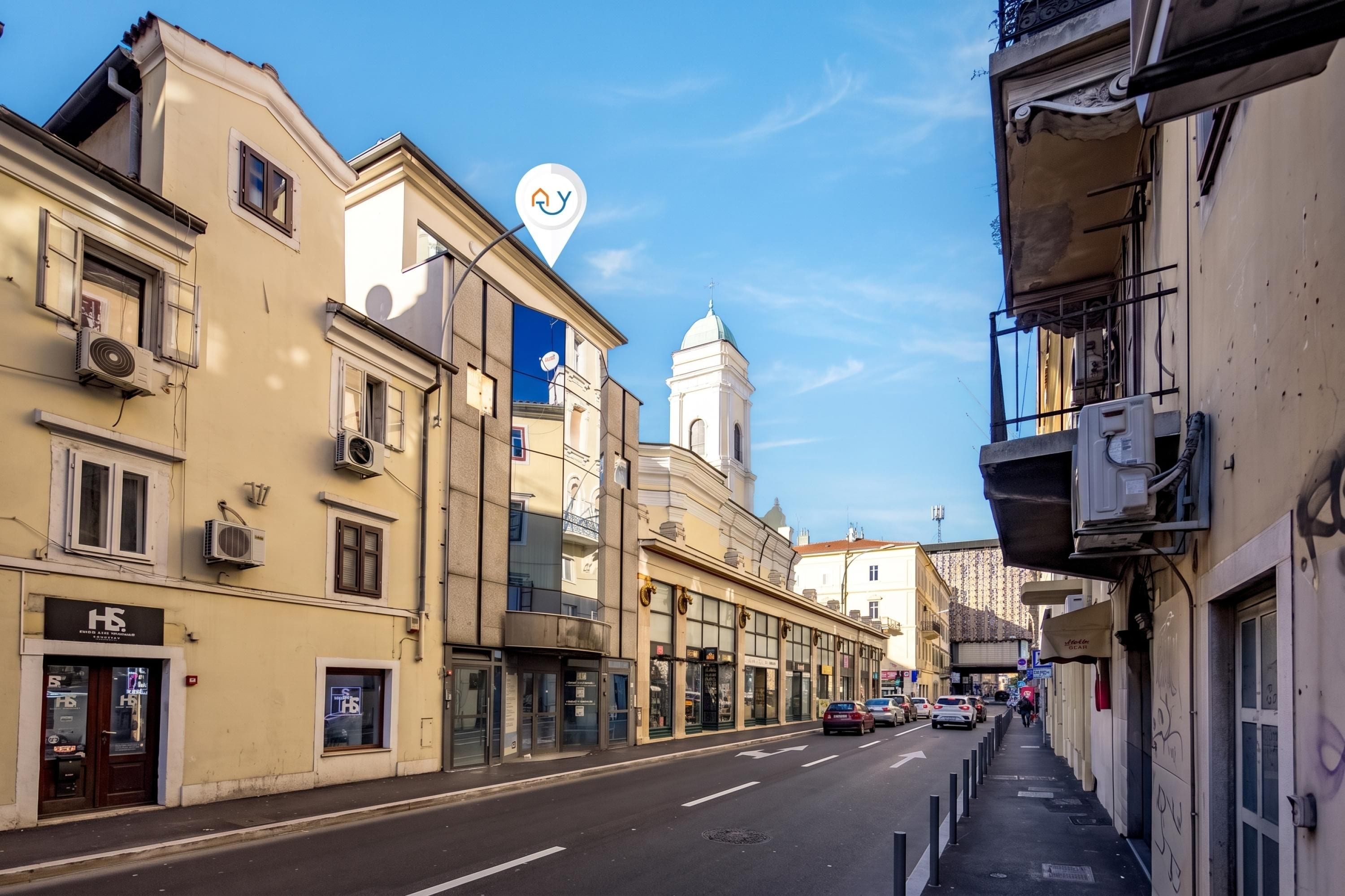 Vista de una calle con edificios, cielo despejado e iglesia con cúpula.